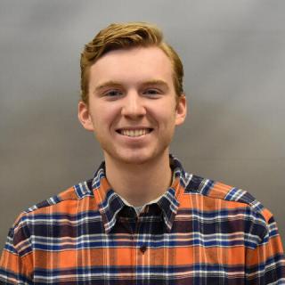 Casey Coughlin smiling and wearing a plaid shirt