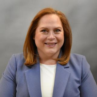 Laura Alvarez smiling and wearing a purple jacket